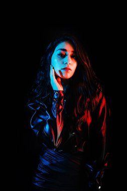 Latin Amerika 'nın siyah arka planında siyah renkli kırmızı-mavi ışıkları olan siyah elbiseli genç Latin kadın.