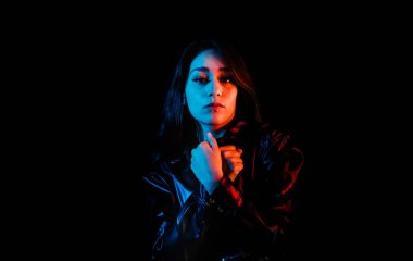 Latin Amerika 'nın siyah arka planında siyah renkli kırmızı-mavi ışıkları olan siyah elbiseli genç Latin kadın.