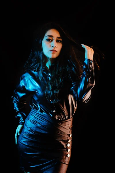 young latin woman dressed in black clothes with colorful red-blue lights on black background in Mexico Latin America