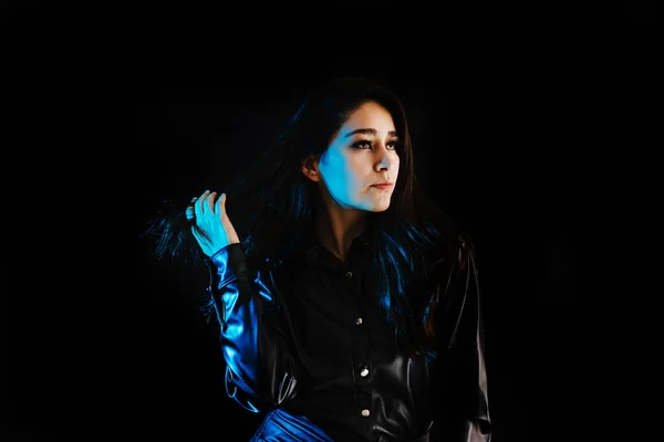 young latin woman dressed in black clothes with colorful red-blue lights on black background in Mexico Latin America