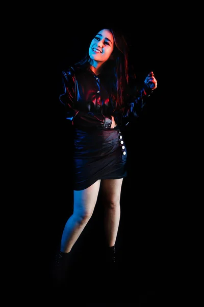 young latin woman dressed in black clothes with colorful red-blue lights on black background in Mexico Latin America