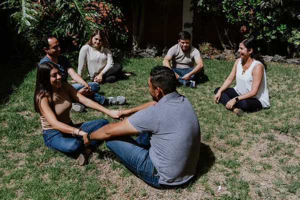 hispanic young couple seated in circle on grass and participating in group therapy session in Mexico Latin America