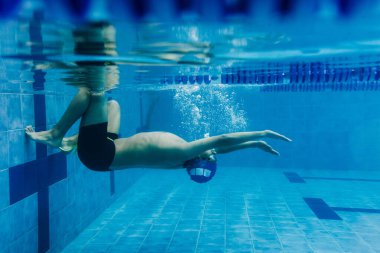 Latin genç erkek yüzücü, başlık takıp gözlük takıyor ve Meksika 'daki havuzda yüzüyor.