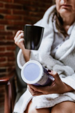 relaxed hispanic mature middle aged woman reading a book at home and drinking tea sitting at bedroom in Mexico Latin America