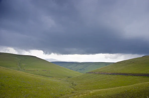 Green hills below storm clouds — Stock Photo, Image