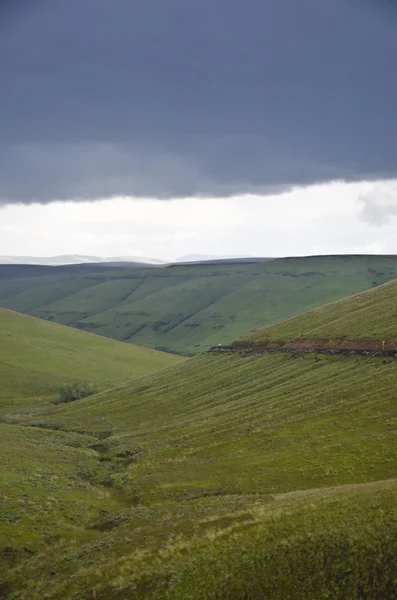 Green hills below storm clouds — Stock Photo, Image