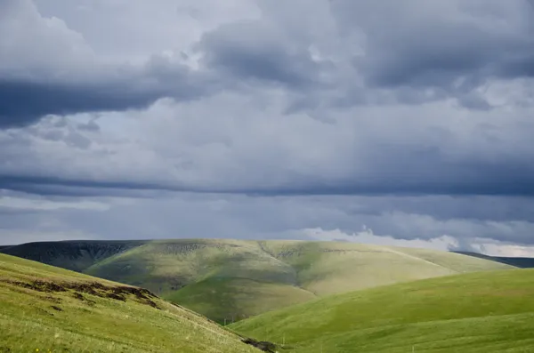 Colinas verdes bajo nubes de tormenta — Foto de Stock