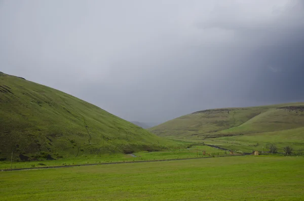 Green hills below storm clouds Stock Picture
