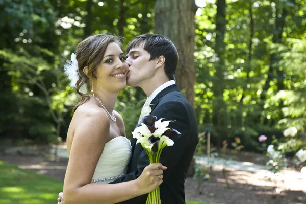 Les jeunes mariés s'embrassent — Photo