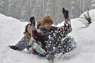 Teens sledding on a saucer clipart