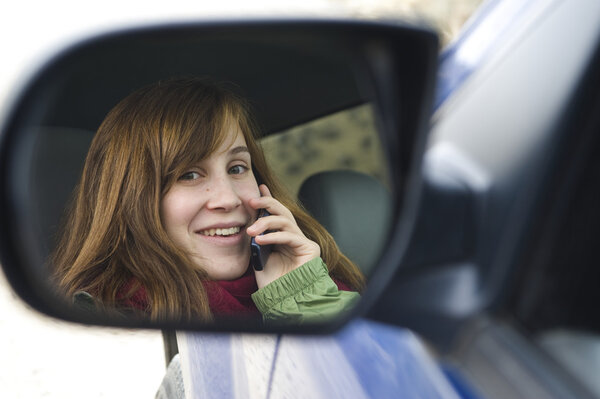 Девушка-подросток разговаривает по мобильному телефону в машине
