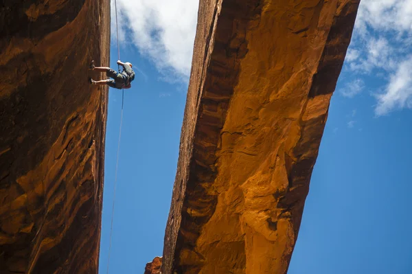 Man rappelling down cliff in desert — Stock Photo, Image