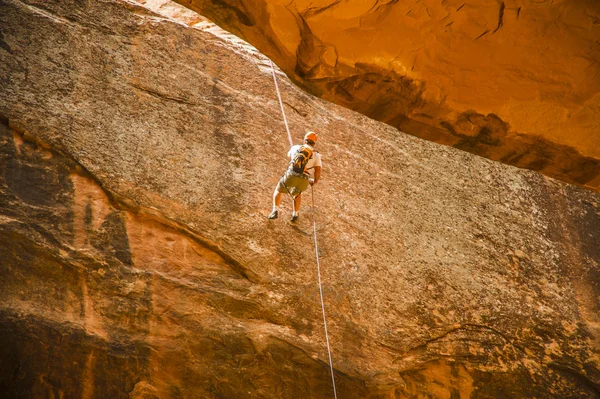 Людина дзвонить вниз по скелі в пустелі — стокове фото
