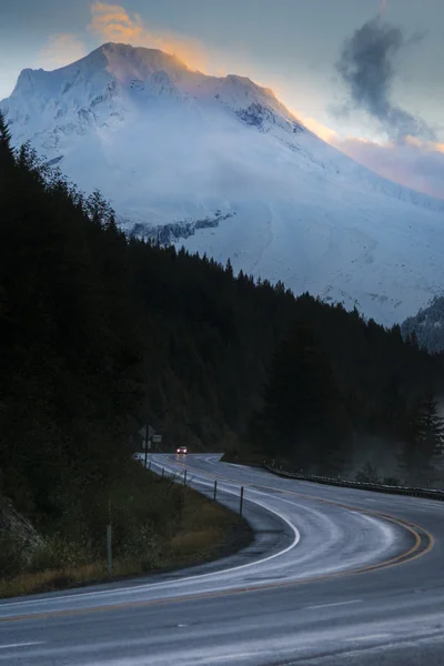 Carretera bajo la montaña nevada al amanecer — Foto de Stock