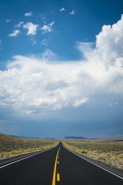 Dark storm clouds above desert highway clipart