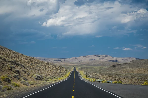 Nuvens de tempestade escuras acima da estrada do deserto — Fotografia de Stock