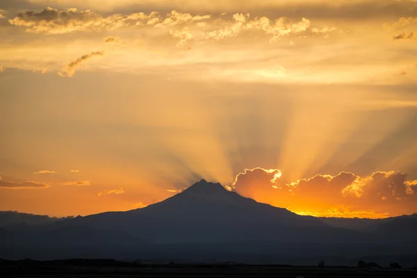 Sunset rays behind silhouette of mountain — Stock Photo, Image