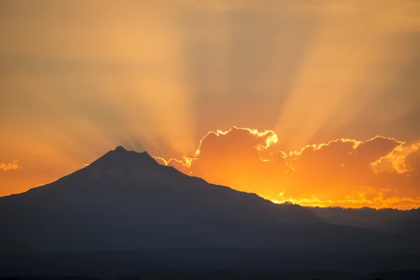 Sunset rays behind silhouette of mountain — Stock Photo, Image
