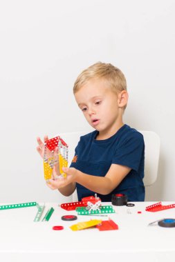 Dikiş, el işi. Küçük çocuk metalden bir çocuk tasarımcısı topluyor.