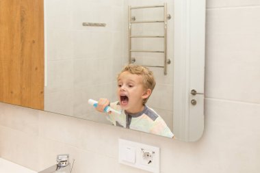 Beş yaşında bir çocuk banyoda ellerini yıkıyor. Beş yaşında, Avrupalı bir çocuk ellerini aynanın önünde banyoda yıkıyor.