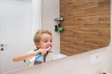 Beş yaşında bir çocuk banyoda ellerini yıkıyor. Beş yaşında, Avrupalı bir çocuk ellerini aynanın önünde banyoda yıkıyor.