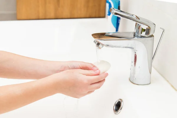 A five-year-old boy washes his hands in the bathroom. A boy of five years old, European outside washes his hands in the bathroom in front of the mirror