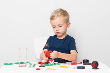 Küçük bir çocuk metalden çocuk tasarımcısı topluyor. Beş yaşında bir çocuk bir inşaatçı topluyor.