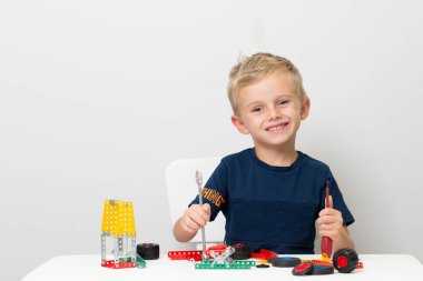 Küçük bir çocuk metalden çocuk tasarımcısı topluyor. Beş yaşında bir çocuk bir inşaatçı topluyor.