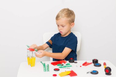 Küçük bir çocuk metalden çocuk tasarımcısı topluyor. Beş yaşında bir çocuk bir inşaatçı topluyor.