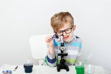 Çocuk beş yaşında, renkli sıvılarla deney yapıyor. Avrupa görünümlü küçük bir bilim adamının kimyasal deneyleri..