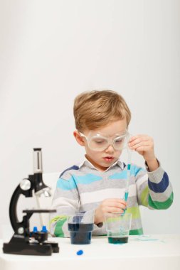 Çocuk beş yaşında, renkli sıvılarla deney yapıyor. Avrupa görünümlü küçük bir bilim adamının kimyasal deneyleri..