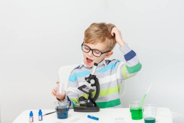 Çocuk beş yaşında, renkli sıvılarla deney yapıyor. Avrupa görünümlü küçük bir bilim adamının kimyasal deneyleri..