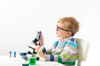 Çocuk beş yaşında, renkli sıvılarla deney yapıyor. Avrupa görünümlü küçük bir bilim adamının kimyasal deneyleri..