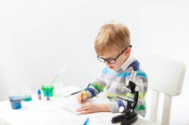 Çocuk beş yaşında, renkli sıvılarla deney yapıyor. Avrupa görünümlü küçük bir bilim adamının kimyasal deneyleri..
