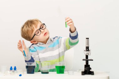 Çocuk beş yaşında, renkli sıvılarla deney yapıyor. Avrupa görünümlü küçük bir bilim adamının kimyasal deneyleri..