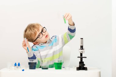Çocuk beş yaşında, renkli sıvılarla deney yapıyor. Avrupa görünümlü küçük bir bilim adamının kimyasal deneyleri..