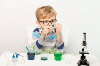 Çocuk beş yaşında, renkli sıvılarla deney yapıyor. Avrupa görünümlü küçük bir bilim adamının kimyasal deneyleri..