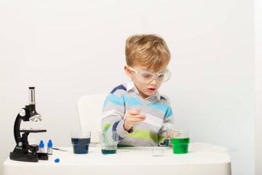 Çocuk beş yaşında, renkli sıvılarla deney yapıyor. Avrupa görünümlü küçük bir bilim adamının kimyasal deneyleri..