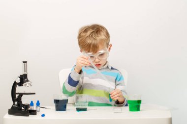 Çocuk beş yaşında, renkli sıvılarla deney yapıyor. Avrupa görünümlü küçük bir bilim adamının kimyasal deneyleri..