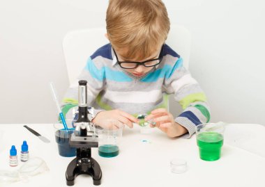 Çocuk beş yaşında, renkli sıvılarla deney yapıyor. Avrupa görünümlü küçük bir bilim adamının kimyasal deneyleri..