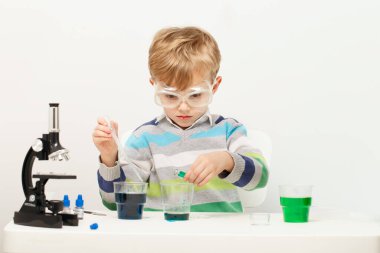 Çocuk beş yaşında, renkli sıvılarla deney yapıyor. Avrupa görünümlü küçük bir bilim adamının kimyasal deneyleri..