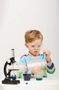 Çocuk beş yaşında, renkli sıvılarla deney yapıyor. Avrupa görünümlü küçük bir bilim adamının kimyasal deneyleri..