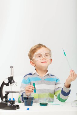 Çocuk beş yaşında, renkli sıvılarla deney yapıyor. Avrupa görünümlü küçük bir bilim adamının kimyasal deneyleri..