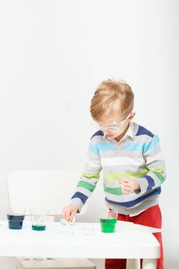 Çocuk beş yaşında, renkli sıvılarla deney yapıyor. Avrupa görünümlü küçük bir bilim adamının kimyasal deneyleri..