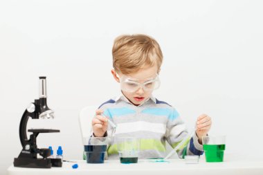 Çocuk beş yaşında, renkli sıvılarla deney yapıyor. Avrupa görünümlü küçük bir bilim adamının kimyasal deneyleri..