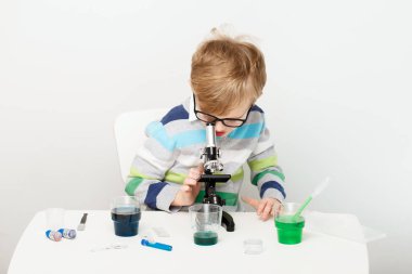 Çocuk beş yaşında, renkli sıvılarla deney yapıyor. Avrupa görünümlü küçük bir bilim adamının kimyasal deneyleri..