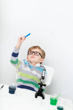 Çocuk beş yaşında, renkli sıvılarla deney yapıyor. Avrupa görünümlü küçük bir bilim adamının kimyasal deneyleri..