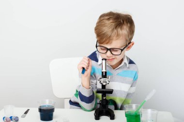 Çocuk beş yaşında, renkli sıvılarla deney yapıyor. Avrupa görünümlü küçük bir bilim adamının kimyasal deneyleri..