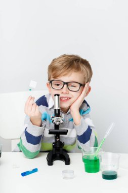 Çocuk beş yaşında, renkli sıvılarla deney yapıyor. Avrupa görünümlü küçük bir bilim adamının kimyasal deneyleri..