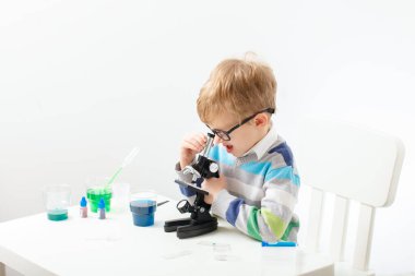 Çocuk beş yaşında, renkli sıvılarla deney yapıyor. Avrupa görünümlü küçük bir bilim adamının kimyasal deneyleri..
